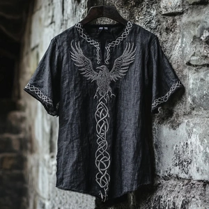 Close-up of V-neck shirt with detailed crow and Celtic knot embroidery on gray fabric