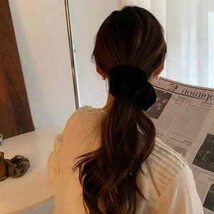 Elegant large black velvet scrunchie with pearl accent worn by a model in soft lighting