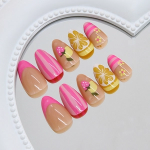 Almond press-on nails with strawberry, lemon, and daisy patterns on a white tray
