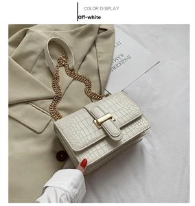 Close-up of off-white faux leather handbag featuring crocodile texture and gold hardware