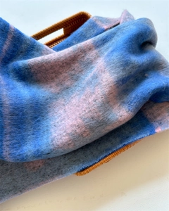 Close-up of soft blue and pink checkered tassel scarf folded on a wicker basket
