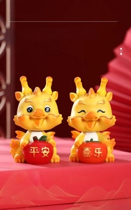 Detail of two resin dragon figurines holding apple and persimmon for luck and safety