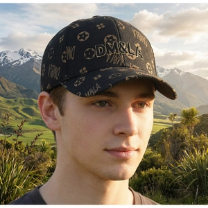 Detail of black baseball cap with gold floral patterns and 3D embroidery against snowy hills