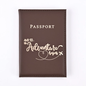 Close-up of dark brown PU leather passport holder with golden adventure-themed engraving