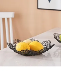 Detail of matte black wavy wire iron fruit basket on a white marble tabletop