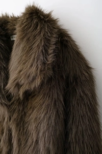 Gros plan d'une veste en fausse fourrure marron avec texture moelleuse et grand col revers