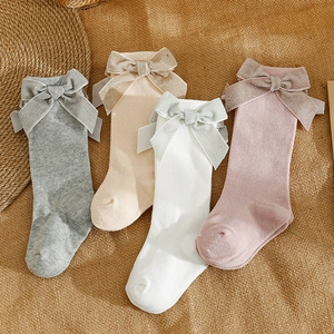 Spanish style baby knee high socks with large bows in four warm colors on linen background