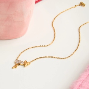 Close-up of 18K gold stainless steel heart and cross pendants with crystal details
