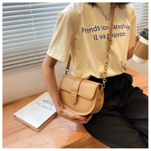 Detail showing the crocodile-embossed pattern and metal buckle on this beige saddle bag
