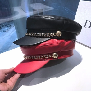 Detailed macro of vintage faux leather baker boy caps with decorative golden chain and buttons