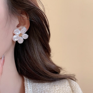 Close-up of elegant pearl flower earrings with gold center worn by a model