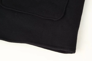 Detailed close-up of premium black wool blend fabric texture and stitching on the coat