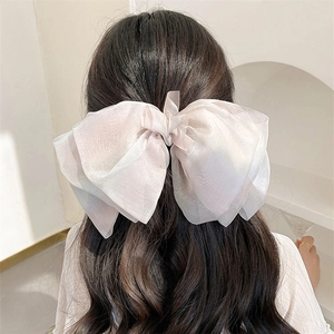 Macro detail of the layered ivory organza fabric on the large bow hair clip accessory