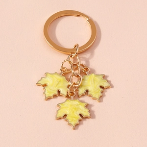 Fashionable golden ginkgo leaf keychain with three yellow charms on a pink background