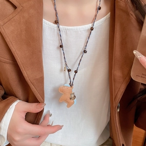 Detailed shot of pony leather pendant on a braided cord necklace with acrylic stone beads