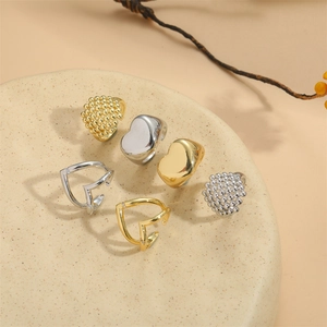 Set of six vintage gold and silver adjustable heart rings on a ceramic jewelry tray