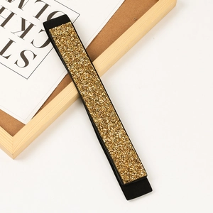 Close-up of golden sequins on black elastic belt with sparkling detail and texture
