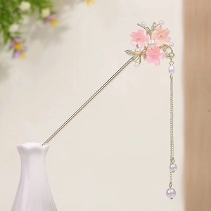 Detailed view of pink cherry blossom hair pin with white pearls and gold tassel charms