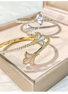 Detailed macro view of 18k gold iris open bangles with zircon and mother of pearl inlay
