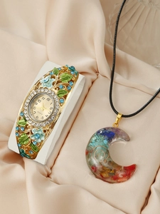Detailed view of cloisonné floral watch and crescent pendant necklace on silk