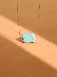 Detailed view of rectangular turquoise pendant on a 18K gold plated stainless steel chain