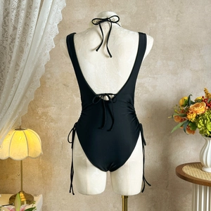 Detailed back view of sexy black backless swimsuit with elegant tie-up lace details