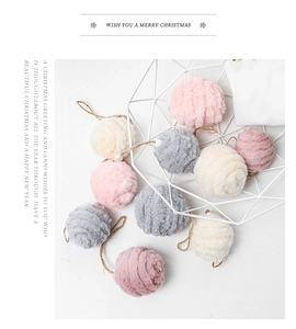 Close-up of soft pink and grey felt pompom Christmas ornaments in a white wire basket