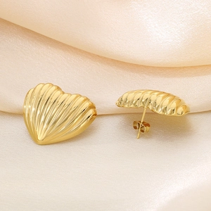Macro shot of 18K gold plated heart stud earrings with vertical striped texture on satin