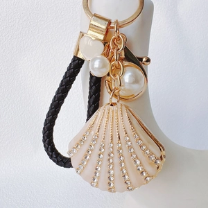 Detail of seashell keychain featuring rows of rhinestones, pearls and a leather loop