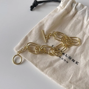 Polished gold double-link 925 silver bracelet with toggle clasp on a canvas bag