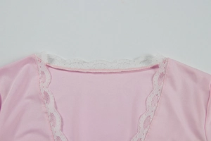Close-up of pink V-neck top showing delicate white floral lace trim on soft fabric