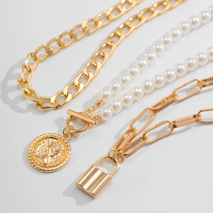 Macro detail of layered gold necklaces with baroque pearl and coin pendant design