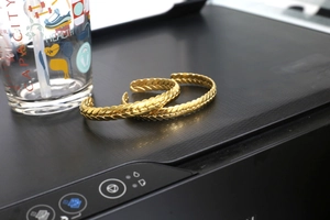 Close-up of golden stainless steel bangle with detailed wheat ear texture and open design