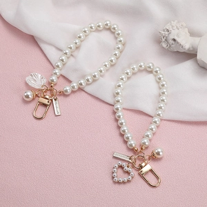 Vintage heart and shell pearl keychain charms for bags or earphones on pink texture background
