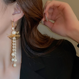 Detail of vintage gold earrings with zirconia, leaf design and long pearl tassels