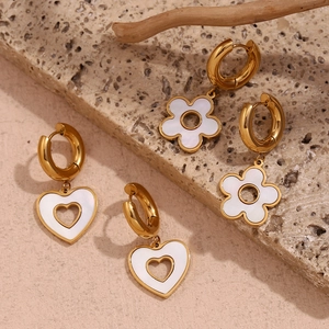 Detailed shot of gold plated stainless steel heart and flower shell earrings on marble