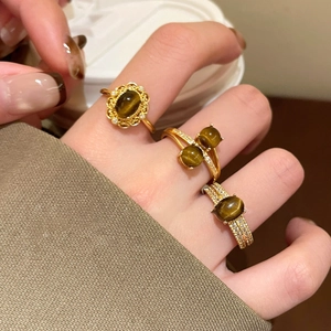 Dettaglio di anelli placcati oro con occhio di tigre e zircone indossati dal modello