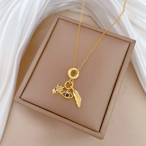 Gold leaf and evil eye pendant necklace with crystals on a beige jewelry box