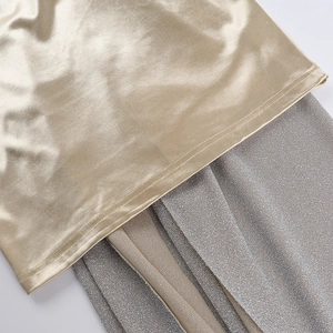 Détail du tissu satiné doré et de la maille pailletée argentée contrastée sur la robe