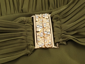 Detail of olive green pleated dress featuring a gold buckle with crystal rhinestone accents