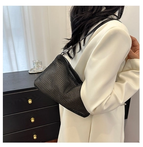 Detail of a black rhinestone underarm bag worn by a model in a modern home setting