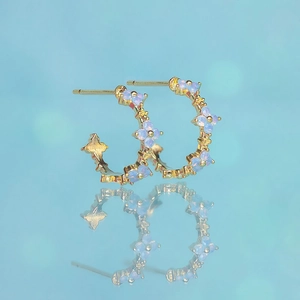 Macro detail of gold flower earrings with blue cubic zirconia and mirror reflection