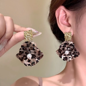 Vintage leopard print flower drop earrings with gold metal and pearls on a model