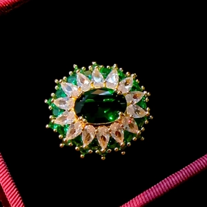 Detail of a gold brooch with an oval emerald stone in a velvet jewelry box