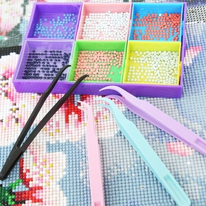 Macro shot of a purple diamond painting tray and colorful nylon tweezers on a canvas