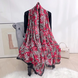 Detail of a red paisley silk scarf draped on a chair showing texture and pattern