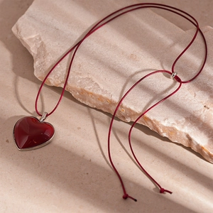 Close-up of red resin heart necklace on stone, minimalist autumn fashion jewelry