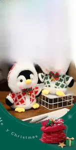 Close-up of plush Christmas penguins in patterned sweaters with bells and a gift bag
