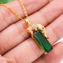 Detailed macro view of a gold cheetah-shaped clasp with a large emerald green stone pendant
