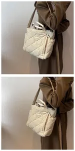 Detail of cream quilted tote bag with cross-body strap and rhombus pattern texture